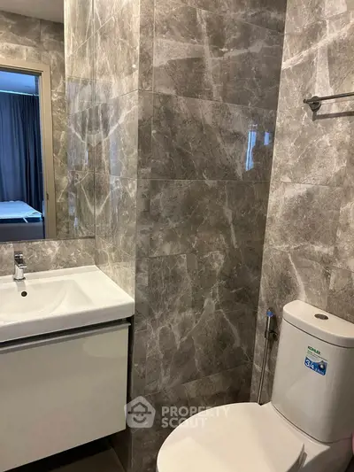 Modern bathroom with sleek marble tiles and contemporary fixtures in a stylish apartment.