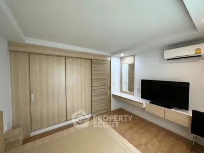 Modern bedroom with built-in wardrobe and wall-mounted TV in minimalist design.