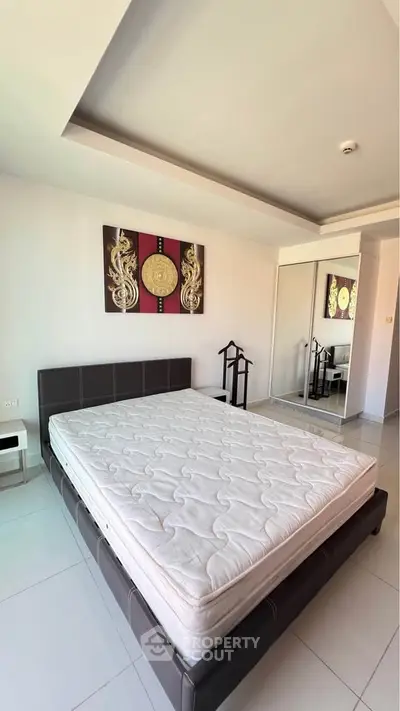 Spacious bedroom with modern decor and large mirror closet in a stylish apartment.
