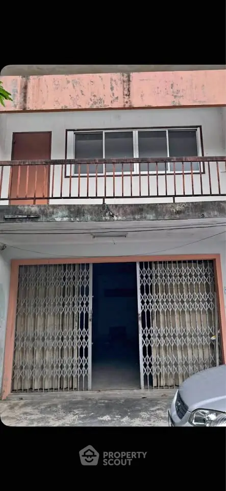 Charming two-story building with gated entrance and balcony, ideal for commercial or residential use.