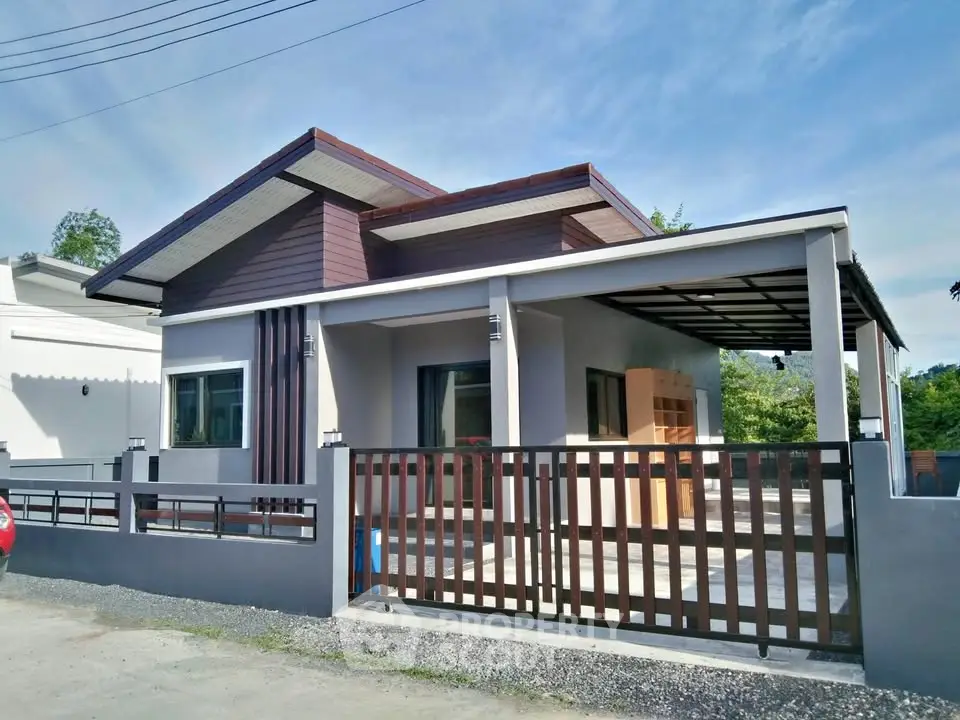 Modern single-story house with sleek design and spacious carport in a serene neighborhood.