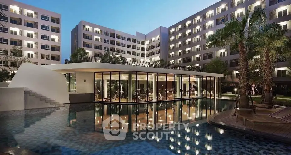 Luxurious modern apartment complex with illuminated pool and gym facilities at dusk.