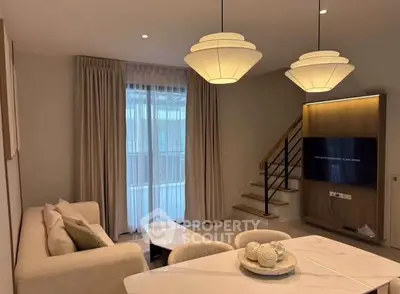 Modern living room with elegant lighting and staircase, featuring a cozy sofa and wall-mounted TV.