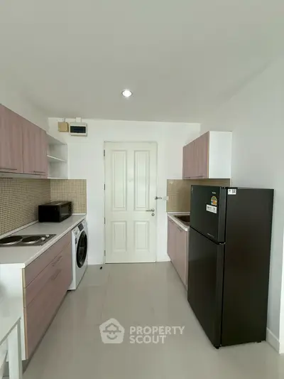 Modern kitchen with sleek appliances and minimalist design, featuring a washing machine and refrigerator.