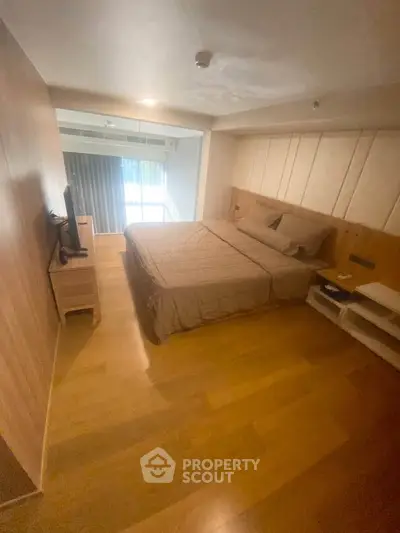 Spacious bedroom with modern decor and natural light, featuring a comfortable bed and wooden flooring.