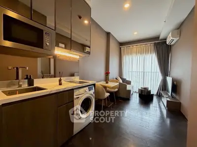 Modern open-plan living room with kitchen, featuring sleek appliances and cozy seating area.