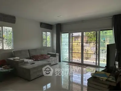 Spacious living room with large windows and modern furnishings, offering a bright and inviting atmosphere.