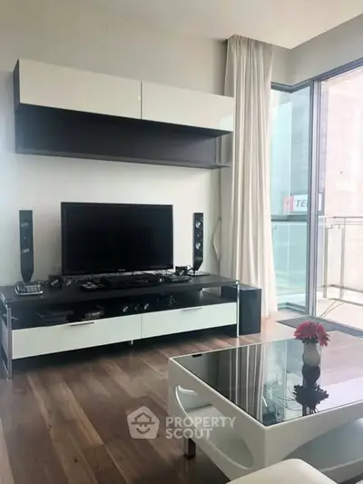 Modern living room with sleek furniture and large window offering natural light and city view.