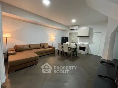 Modern open-plan living room with stylish furniture and kitchen area, perfect for contemporary living.