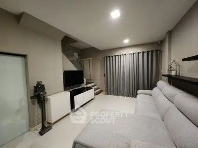 Modern living room with sleek design, featuring a cozy gray sofa and stylish entertainment unit.