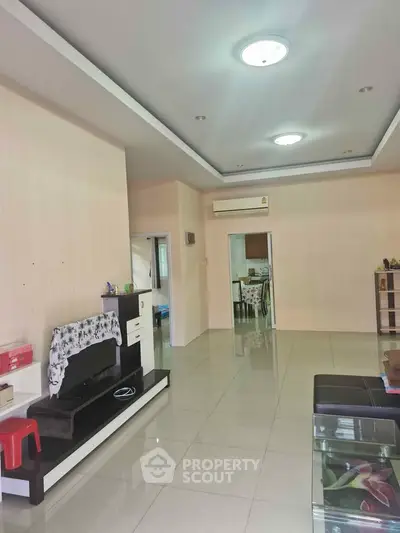 Spacious living room with modern decor and open layout, featuring sleek tile flooring and ambient lighting.