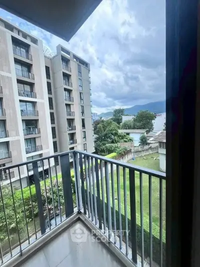 Modern apartment balcony with scenic view of lush greenery and contemporary building.
