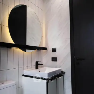 Modern bathroom with stylish round mirror and sleek fixtures