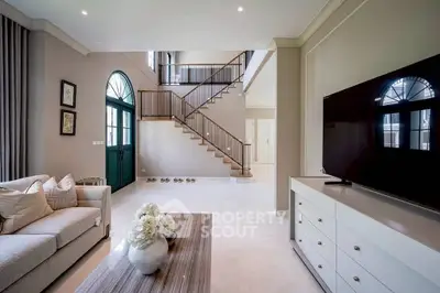 Elegant living room with high ceilings, modern staircase, and stylish decor in a luxury home.