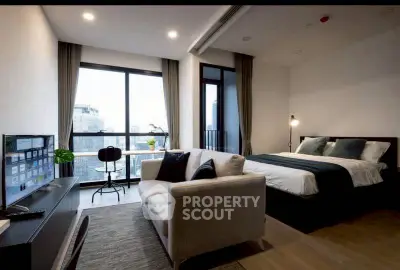 Modern studio apartment with city view, featuring cozy bed, sofa, and work desk.