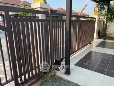 Modern residential entrance with sleek metal gate and tiled pathway.