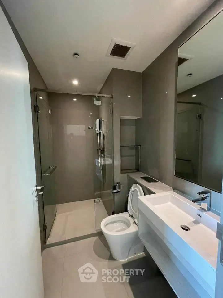 Modern bathroom with sleek design, featuring a glass shower enclosure and contemporary fixtures.