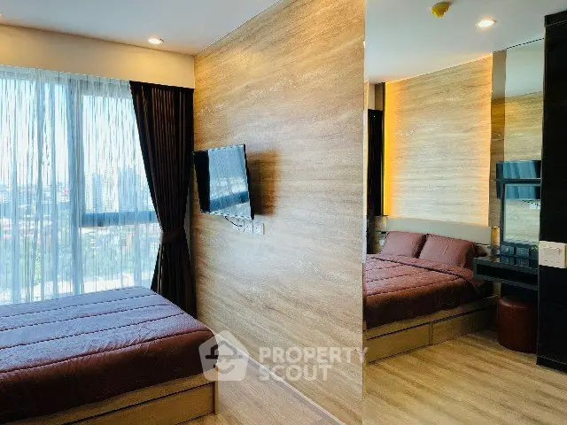 Modern bedroom with large window and wall-mounted TV in stylish apartment.