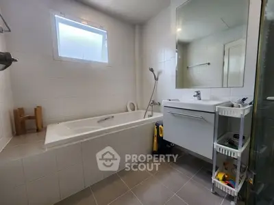 Modern bathroom with bathtub and sleek vanity in a bright, tiled space.