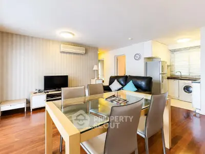 Modern open-plan living room with dining area and kitchen, featuring sleek furniture and hardwood floors.
