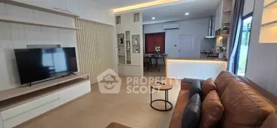 Modern living room with stylish decor and open layout, featuring a large TV and cozy seating area.