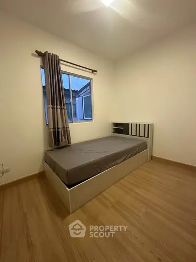 Cozy bedroom with single bed and window view, perfect for minimalist living.