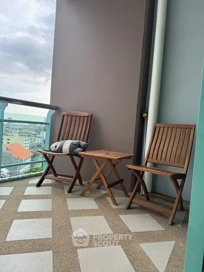 Charming balcony with city view, featuring wooden chairs and table, perfect for relaxation.