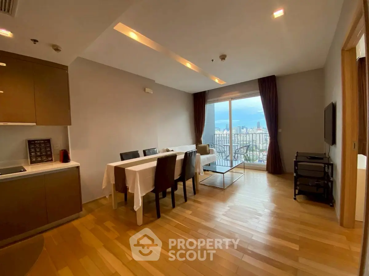 Modern dining area with city view, featuring sleek furniture and wooden flooring.