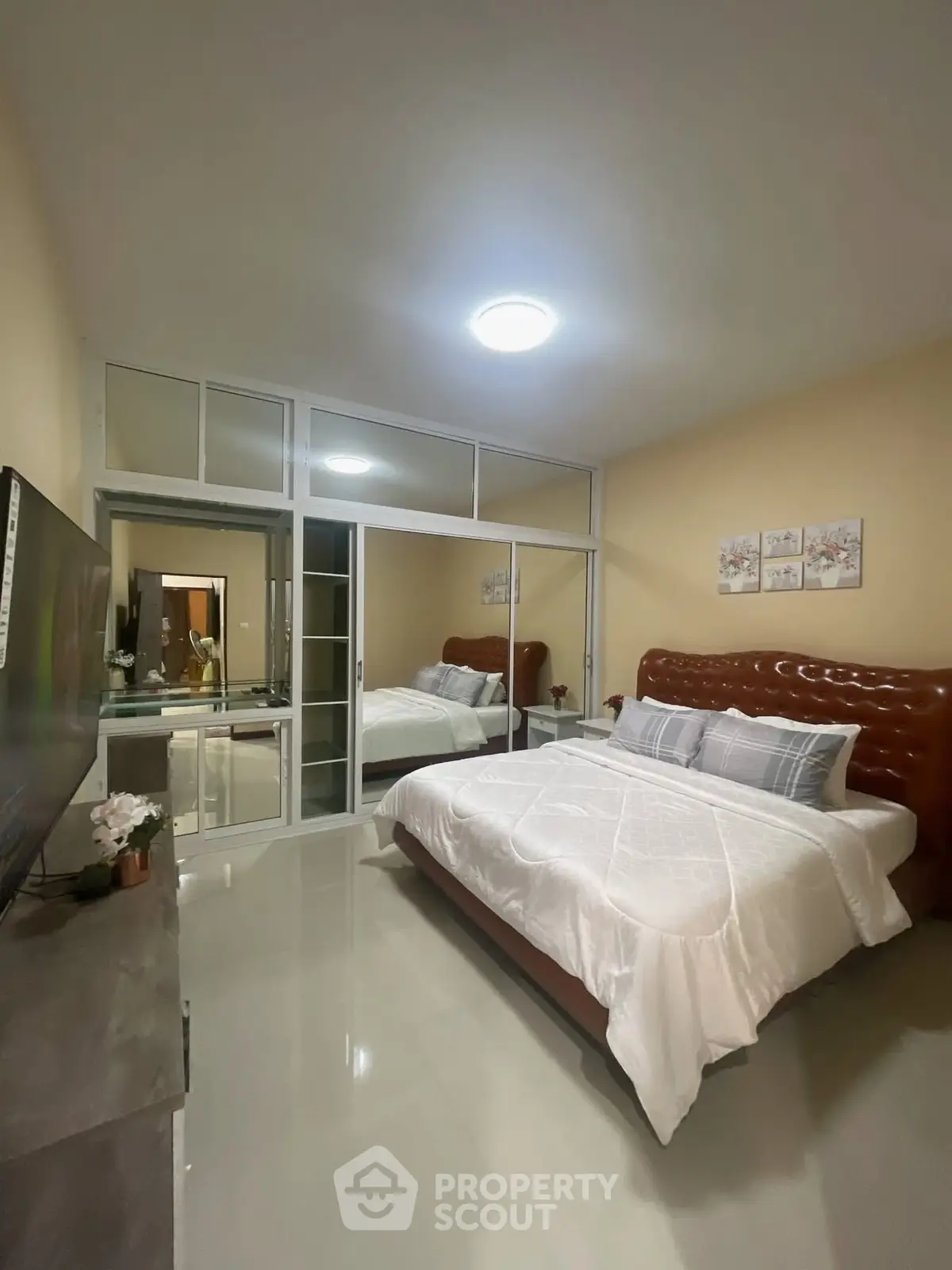 Spacious bedroom with modern decor and large mirrored wardrobe