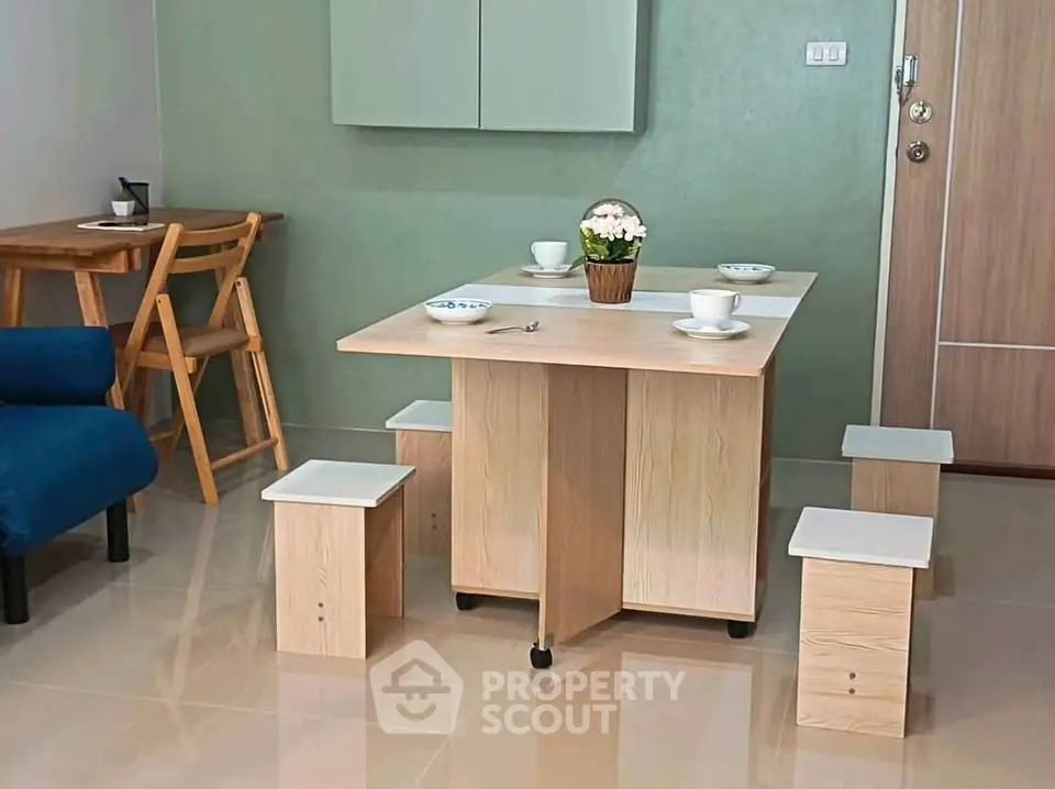 Modern dining area with compact wooden table and stools in cozy apartment setting.