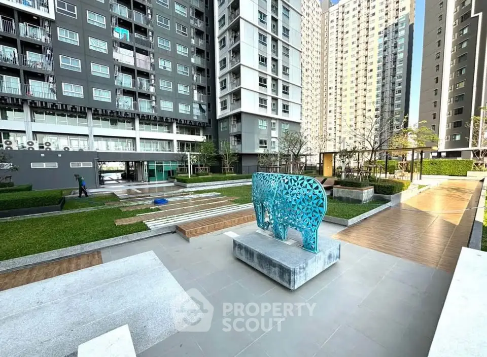 Modern apartment complex with landscaped garden and artistic sculpture