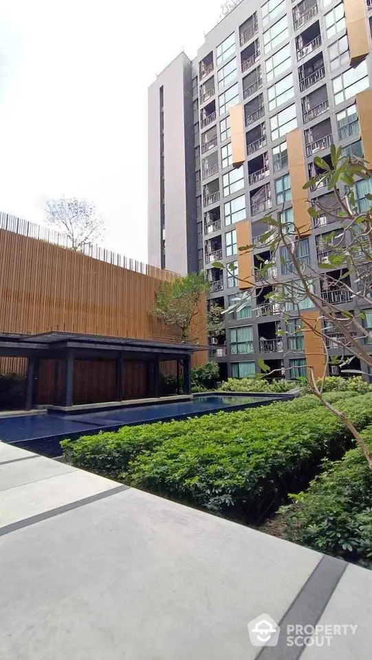 Modern apartment building with lush garden and pool view