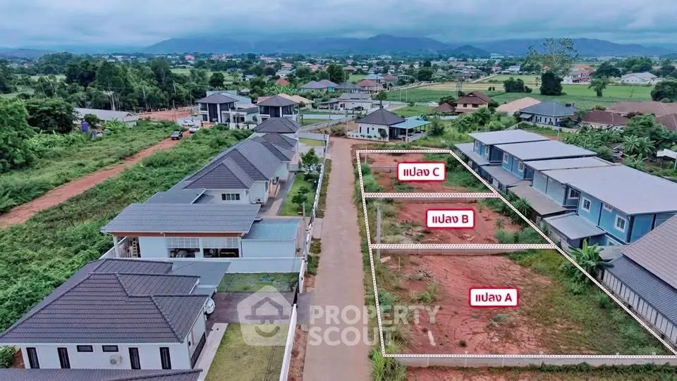 Aerial view of residential plots in a serene neighborhood with mountain backdrop.
