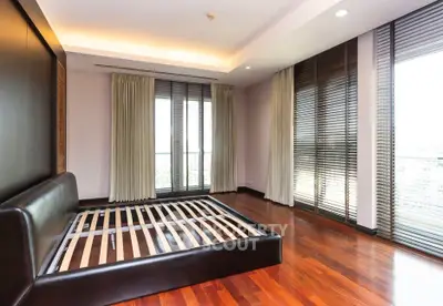 Spacious bedroom with large windows and wooden flooring in modern apartment