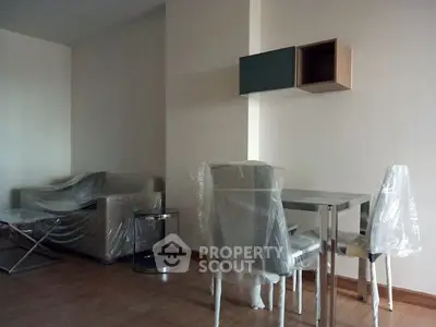 Modern living room with furniture wrapped in protective plastic, ready for move-in.