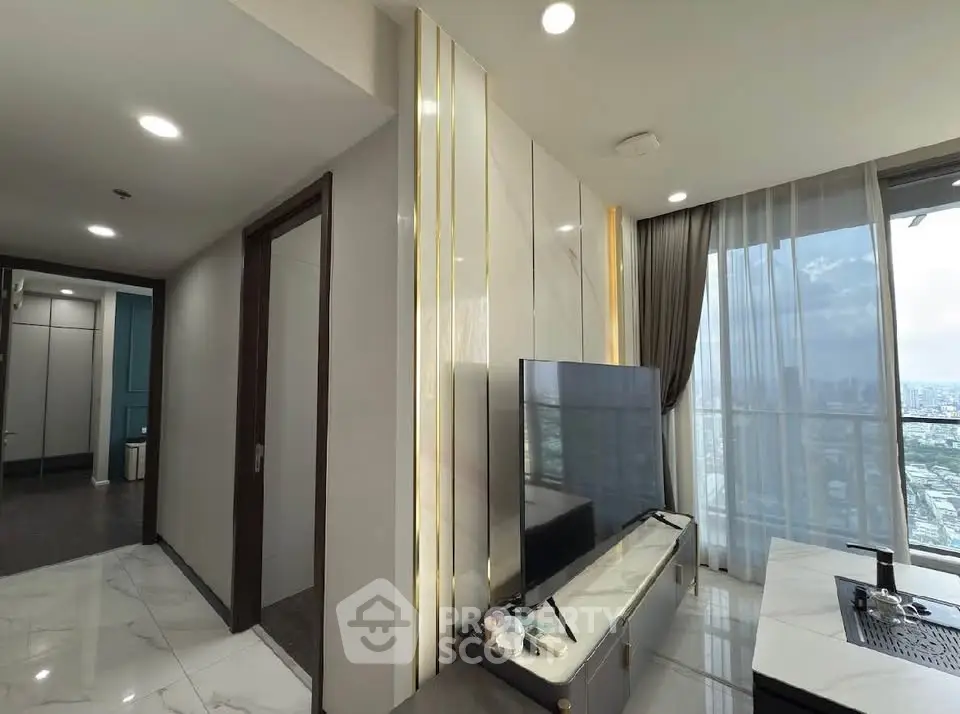 Modern living room with city view, sleek TV setup, and elegant decor in high-rise apartment.