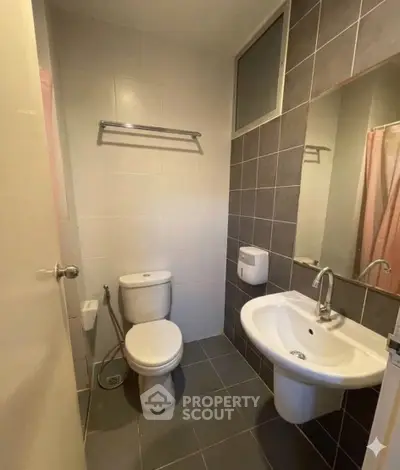 Compact bathroom with modern fixtures and neutral tiles, ideal for efficient space utilization.