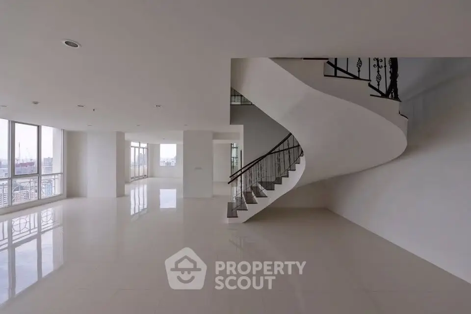 Spacious modern living room with elegant staircase and panoramic city views.