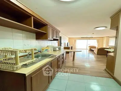 Spacious open layout kitchen and living room with wooden cabinetry and modern appliances.