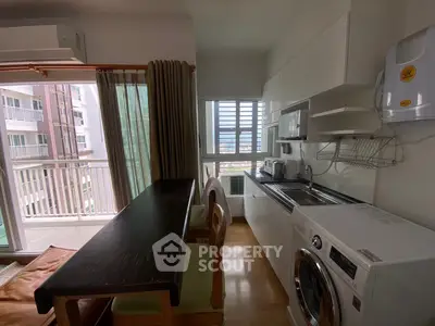 Modern kitchen with balcony view, featuring sleek appliances and compact dining area in a stylish apartment.