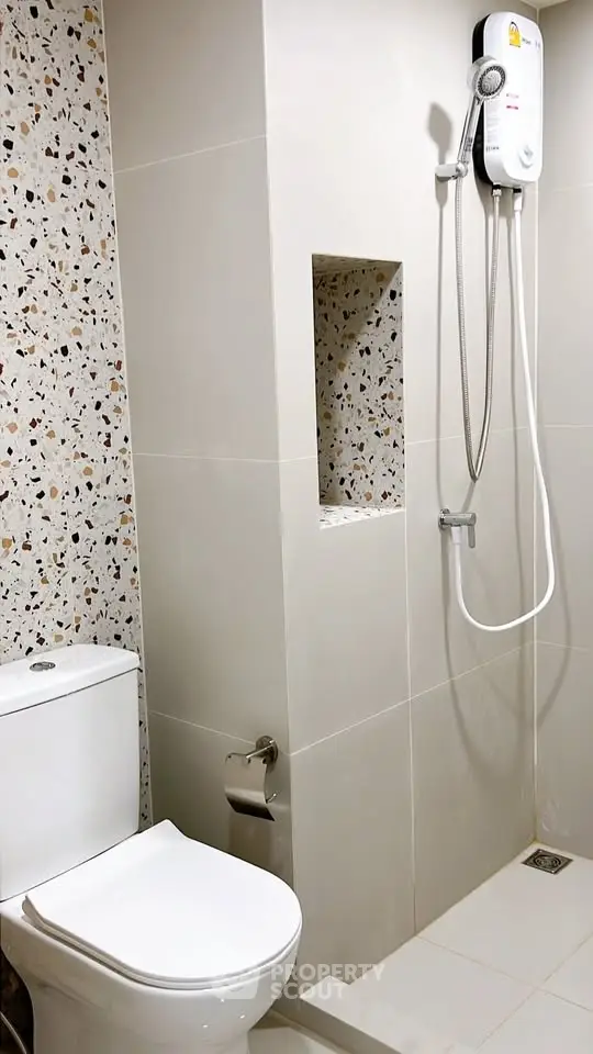 Modern bathroom with sleek shower and terrazzo tiles, perfect for contemporary living.