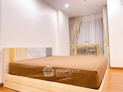 Spacious bedroom with modern decor and large window in a stylish apartment.