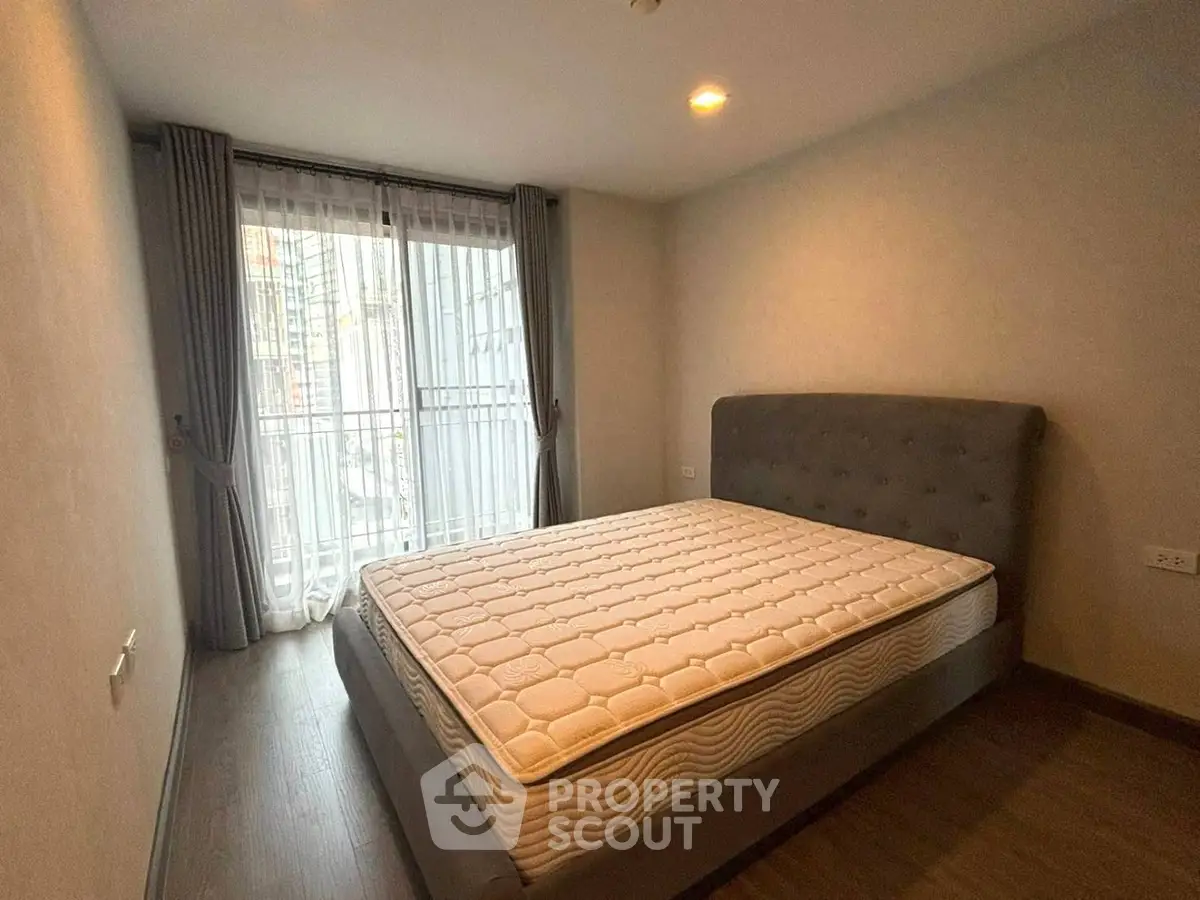 Spacious bedroom with large window and modern bed in a stylish apartment.