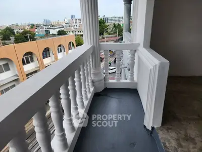 Charming balcony with classic railing offering urban views in a vibrant neighborhood.