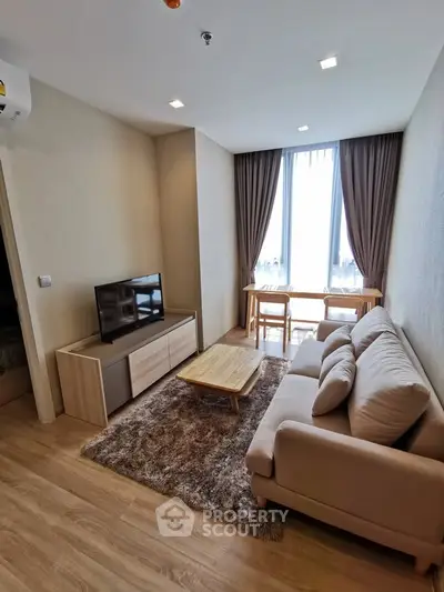Modern living room with cozy sofa, TV, and dining area in a bright apartment.