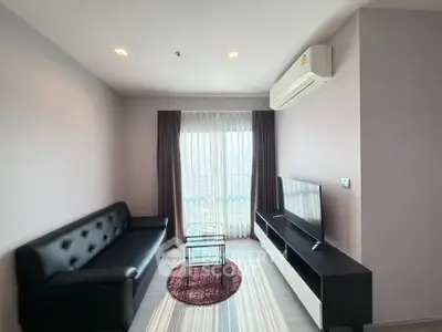 Modern living room with sleek black sofa and large TV, bright natural light