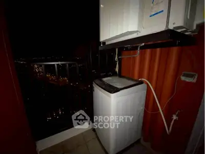 Compact balcony with washing machine and city night view, ideal for urban living.