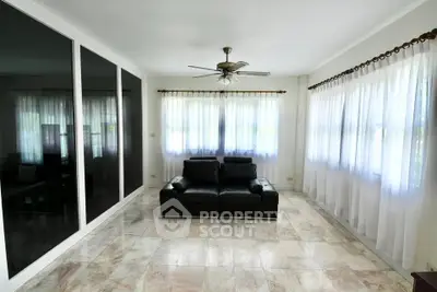 Spacious living room with elegant black sofa and large windows for natural light.