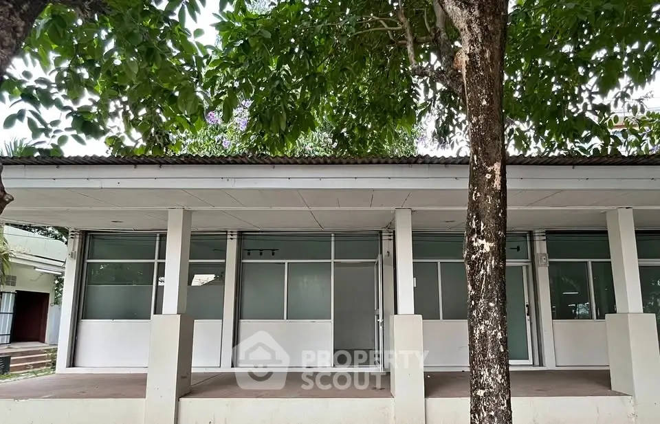 Charming commercial property with large windows and lush greenery, ideal for business opportunities.