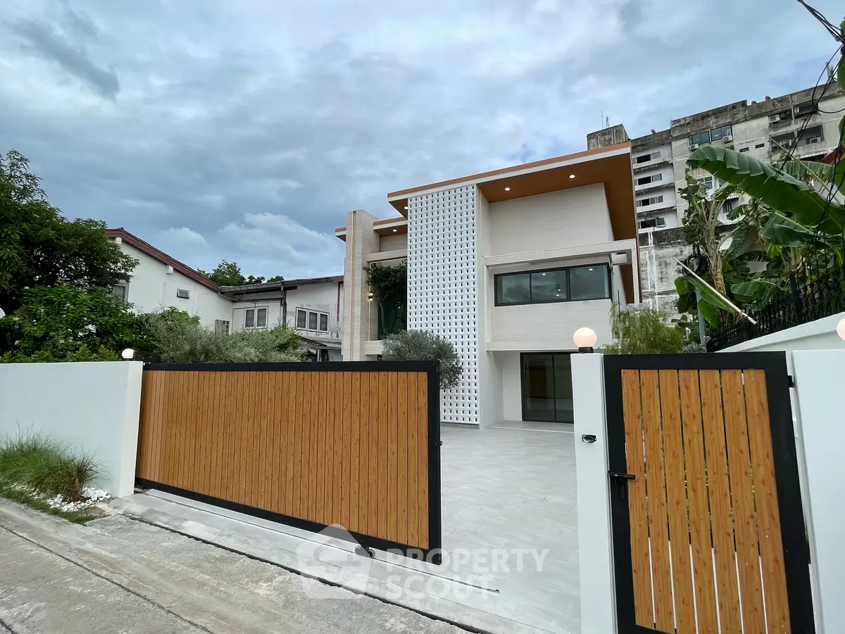 Modern two-story house with wooden gate and contemporary facade in urban setting.